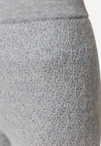 Nahaufnahme eines weichen grauen Strickstoffs mit gerippetem Bund und aufwändigem, strukturiertem Muster auf warmer Kleidung.