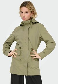 Parka imperméable vert olive avec une capuche, une taille ajustable par cordon et deux poches avant. Texture lisse et poignets réglables.