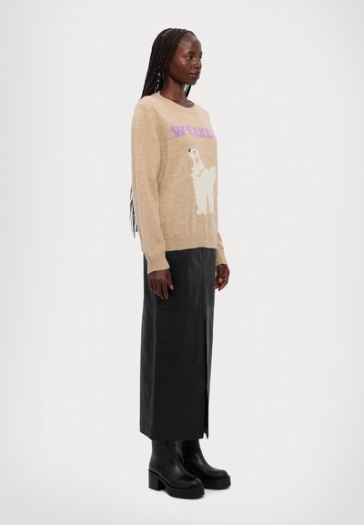 Pull beige clair avec du texte violet "WEEKEND" et un design de chien fluffy blanc, associé à une jupe en cuir noir et des bottes noires épaisses.
