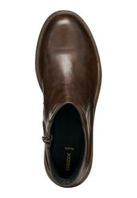 Zapato slip-on de cuero marrón con un acabado suave, puntera redondeada, cremallera lateral y forro interior negro. Presenta detalles de costura sutiles.