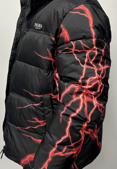 Giubbotto imbottito nero con motivi a saetta rossa sulle maniche. Il materiale sembra liscio, con chiusura a zip e dettaglio del logo.