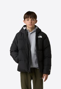 Fekete, kapucnis pufi dzseki steppelt mintával és egy kis logóval. Szürke pulóver fölött viselve, olíva zöld nadrággal párosítva.