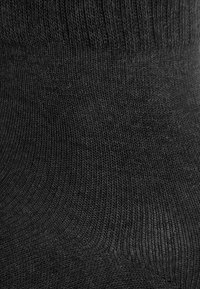 Schwarze Baumwollsocke mit geripptem Muster und glatter Oberfläche, ausgestattet mit einer nahtlosen Zehenpartie für zusätzlichen Komfort und einer optimalen Passform um den Knöchel.
