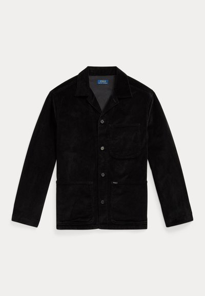 Giacca di velluto a costine nera con colletto a punta, bottoni frontali, taschino sul petto e due tasche inferiori. Texture liscia e design classico.