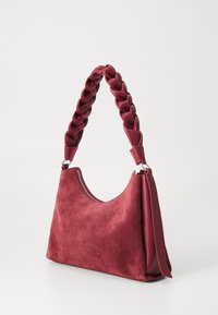 Red suede shoulder bag with a braided handle and a zippered opening. The bag has a soft, structured design and is displayed on a white background.
