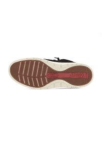 Suola di scarpa atletica nera con una superficie in gomma marrone texture, caratterizzata da scanalature profonde e una intersuola bianca con un accento rosso.