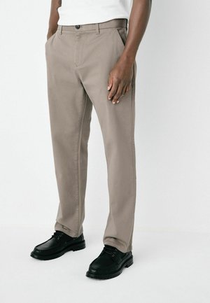 Beige chinos with a straight-leg design, crafted from cotton blend fabric. Features front pockets and a single button closure, paired with black shoes.