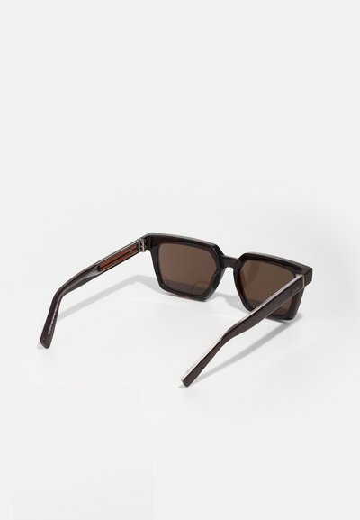 Brown-tinted sunglasses with a hexagonal frame made of glossy black acetate. Features slender arms with silver accents at the hinges.