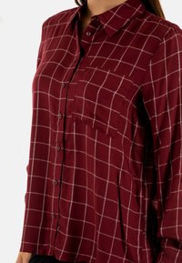 Camicia bordeaux con bottoni, motivo a rete bianca, maniche lunghe, taschino sul petto e tessuto morbido.