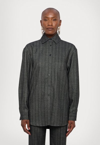Chemise boutonnière gris foncé en tissu texturé, avec des rayures verticales, un col pointu et des manches longues.