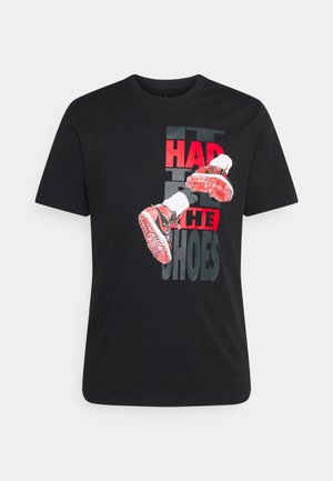 Sort t-shirt med grafik af røde sneakers og teksten "It had to be the shoes" i røde og grå bogstaver.
