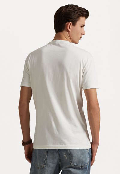T-shirt en coton blanc à manches courtes, col rond et dos uni. Associé à un jean en denim bleu clair.