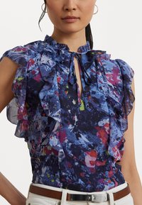Floral blouse in navy with ruffle details, short sleeves, and a keyhole neckline. Features vibrant splashes of pink and green. Textured fabric.