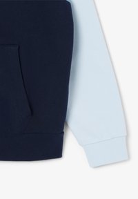 Bluza z kapturem w kolorze blokowym granatowo-błękitnym, z kieszenią kangurzą i ściśle dzianinowymi mankietami. Wykonana z miękkiej mieszanki bawełny.