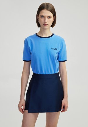 T-shirt in cotone blu con colletto e maniche a coste navy, con un piccolo logo ricamato. Abbinato a una gonna svasata navy.