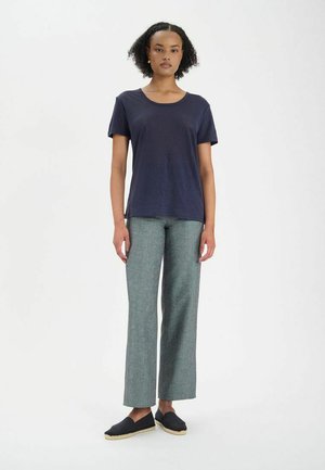 T-shirt bleu marine à manches courtes, associé à un pantalon ample gris clair et des espadrilles bleu marine. Design simple et texture douce.