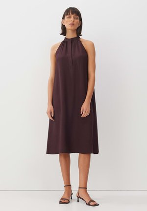 Bordeauxfarbendes Halsbandkleid mit plissiertem Ausschnitt und lockerer A-Linie. Kombiniert mit schnallenfreien Sandalen mit niedrigen Absätzen.