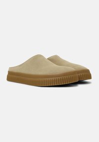 Béžové semišové nazouvací boty s oblým designem, které mají vroubkovanou hnědou gumovou podrážku. Hladký povrch a minimalistický styl.