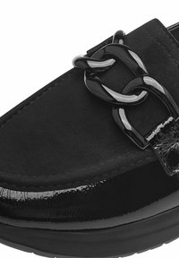Mocassin en daim noir avec détail chaîne noire brillante et garniture en cuir verni sur une semelle en caoutchouc basse.