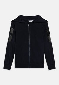 Felpa con zip color navy realizzata in tessuto morbido, con un ampio cappuccio, polsini a costine e dettagli neri lucidi sulle maniche con un numero.