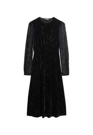 Zwarte fluwelen jurk met lange kanten mouwen, ronde halslijn en een aansluitende lijfje die overgaat in een uitlopende rok. Gelaagd stof met glans.