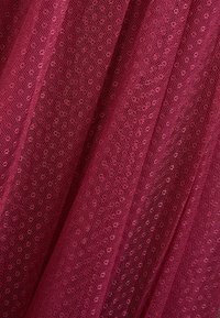 Burgundy nätmaterial med ett texturerat prickmönster, genomskinligt med en lätt och luftig kvalitet, och faller i mjuka veck.