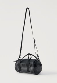 Συμπαγής μαύρη κυλινδρική τσάντα τύπου duffel με ρυθμιζόμενο ιμάντα ώμου, διπλές χειρολαβές και λογότυπο The North Face στην πλαϊνή επιφάνεια, εμφανίζεται σε λευκό φόντο.