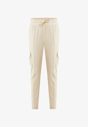 Beżowe spodnie dresowe o tapered fit, z elastycznym paskiem w talii i sznurkiem. Posiadają boczne kieszenie i gładką, lekką tkaninę.