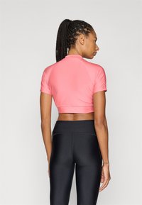 Ροζ κοντομάνικο cropped τοπ με ψηλό γιακά, λείο υλικό και εφαρμοστή σχεδίαση, σε συνδυασμό με μαύρο ψηλόμεσο κολάν.