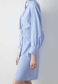 Abito camicia a righe blu e bianche con chiusura a bottoni sul davanti, annodato in vita, con maniche lunghe e voluminose e polsini.