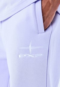 Pantaloni jogging di un leggero lavanda realizzati in morbido tessuto, dotati di una tasca e di un logo ricamato "PXP" con un design a stella in bianco.