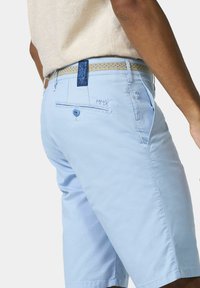 Hellblaue Shorts aus weichem Material, im klassischen Schnitt, mit zwei seitlichen Taschen und einer dekorativen Gesäßtasche mit einem blauen Knopf.