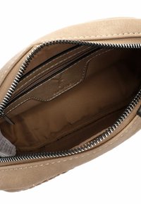 Interno di una borsa in tessuto beige con chiusura a zip, dotato di tasche organizzative e una texture liscia. Dettagli cuciti lungo i bordi.