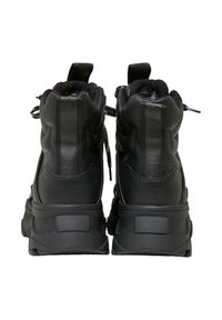 Zapatillas altas negras de cuero texturizado y malla. Presentan un cuello acolchado, etiqueta de tira trasera y suela de goma gruesa.