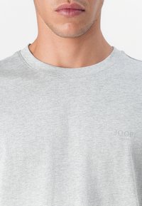Grå bomull crew neck t-skjorte med en subtil logo-print nederst til høyre. Myk, teksturert materiale med et enkelt, klassisk design.