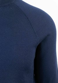 Pullover in maglina blu navy a maniche lunghe con colletto alto. Texture liscia con accenti a coste sul collo e sulle spalle.