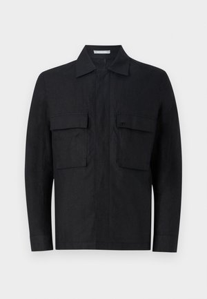 Chaqueta negra de lino con botones y cuello, dos bolsillos delanteros y un diseño minimalista. Presenta un logo sutil en el bolsillo izquierdo.