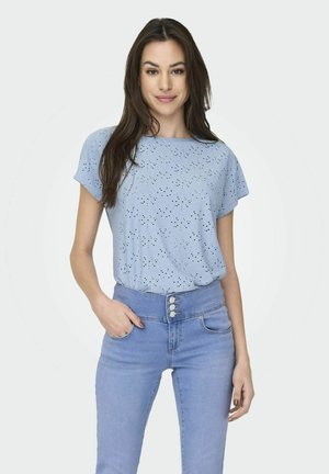 Top azzurro chiaro a maniche corte con dettagli in pizzo, scollatura rotonda e vestibilità rilassata, abbinato a jeans chiari a vita alta con chiusura a bottoni.