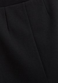 Zwarte stof met een gladde textuur, voorzien van verticale plooien en een nette afwerking, ideaal voor maatwerk of formele kleding.