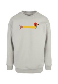 Lys grå sweatshirt med et cartoon-dachshund i en gul frakke med en rød hat og grøn tørklæde, trykt på brystet.