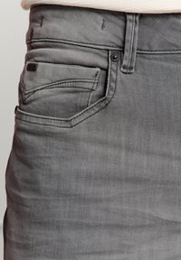 Grijze denim jeans met een vijf-pocket ontwerp, licht vervaagde textuur en een klein logo-tag bij de rechter achterzak.