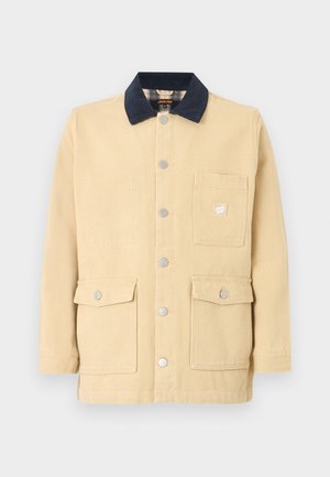 Μπεζ βαμβακερό σακάκι με μαύρο γιακά, κλείσιμο με κουμπιά μπροστά και τρεις μεγάλες τσέπες, μία με μικρό λογότυπο.