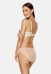 Jasnobeżowy zestaw bielizny składający się z gładkiego biustonosza z regulowanymi ramiączkami oraz dopasowanych przezroczystych majtek z minimalną ilością szwów dla wygody.