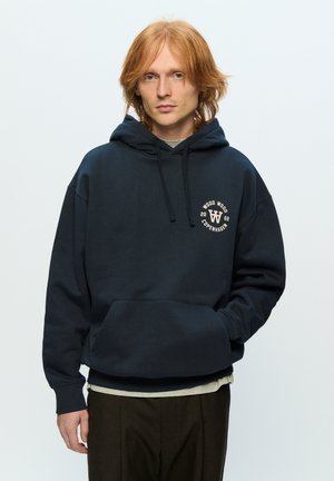 Navy sweatshirt with a hood, front pocket, and circular logo. Made from soft fabric, featuring a relaxed fit and ribbed cuffs.