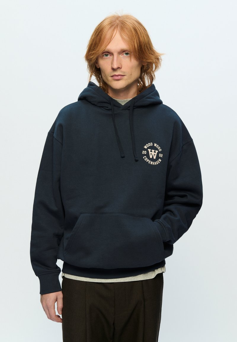 Navy sweatshirt with a hood, front pocket, and circular logo. Made from soft fabric, featuring a relaxed fit and ribbed cuffs.