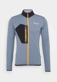 Gray patterned jacket with a high collar, orange zipper, and black pocket accents. Features long sleeves and a fitted design.