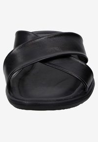 Sandale en cuir noir avec deux lanières croisées, semelle plate et texture lisse. Le design ouvert au niveau des orteils souligne la simplicité et le confort.