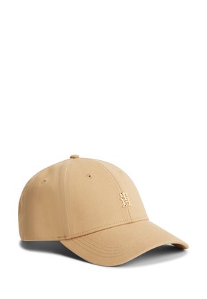 Beige baseball cap with curved brim and stitched ventilation holes, featuring a small gold metallic logo on the front panel.
