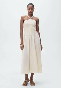 Schulterfreies Midikleid in hellem Creme mit strukturiertem Oberteil und gerafftem Rock. Glattes Material, verstellbare Träger und minimalistisches Design.