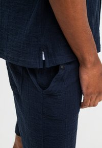 Navy textuur korte mouw top met een zijsplit, gecombineerd met bijpassende shorts met een zichtbare zak en logo label op de tailleband.